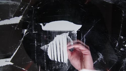 Shooting from below transparent table hand holds credit card cutting dividing cocaine powder