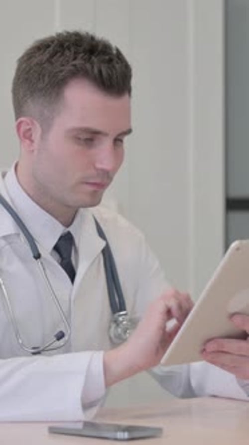 Young Doctor Browsing Tablet in Clinic, vertical video