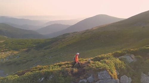 Tourist Hiker with a Backpack in Orange Jacket Walking on Mountain Path in Carpathian Mountains