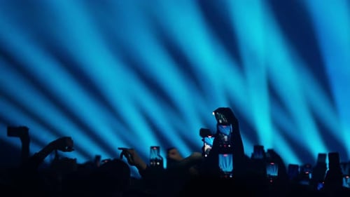 Crowd Cheering at Concert with Blue Stage Lights