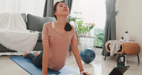 Asia woman in sportswear watching fitness online video on tablet practice yoga for beginner.