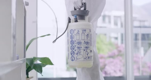 Closeup of sanitation worker disinfecting the inside of an office building