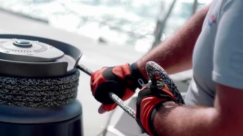 hands pulling a rope in the grip of a sailboat