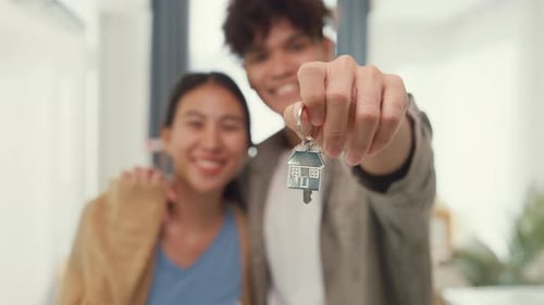 couple hug each other smiling looking at camera so proud show off new house keychain.