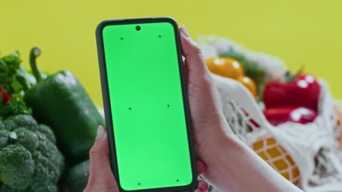 Holding Smartphone with Chroma Key Screen by Fresh Vegetables