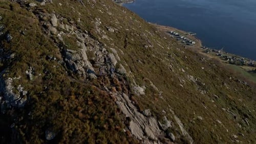 Aerial tilt up shot of hiker group on rocky mountain in Norway with Fjord in the valley