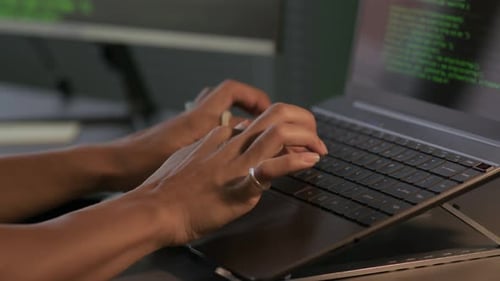 Young Female Programmer Typing Program Code on Laptop in Office at Night