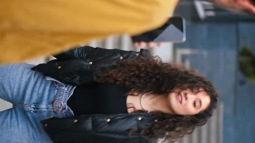 Young Woman Waves at Mobile Phone Vertically