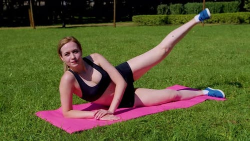 Woman Doing Leg Lifts on Yoga Mat in Park