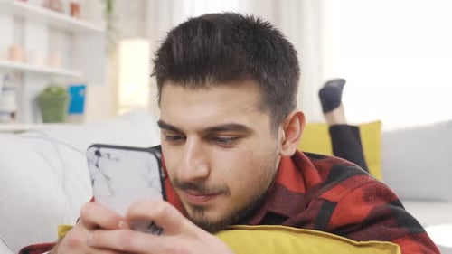 Man Relaxing Indoors Using Phone on Couch
