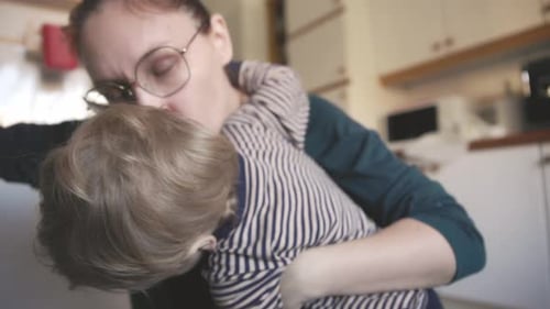 Mother Holds and Kisses Young Child at Home