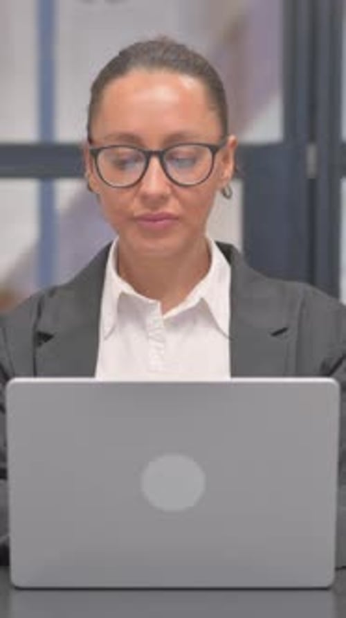 Woman Smiling at Laptop in Office Environment