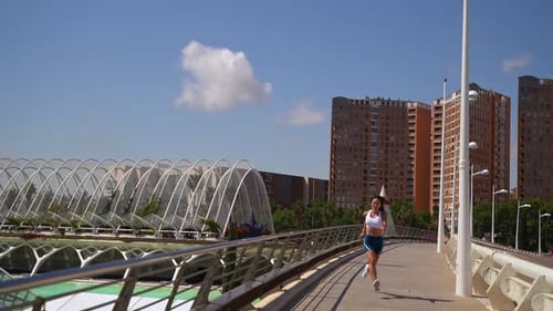 Athletic Woman Jogging on Sunny City Bridge