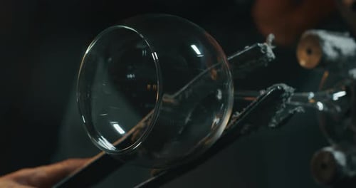 Nahaufnahme eines erfahrenen Glasbläsers in Zeitlupe, der an einem handgefertigten Weinglas aus kostbarem Auto arbeitet