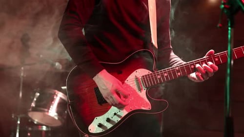 Guitarist playing electric guitar on stage in smokey light