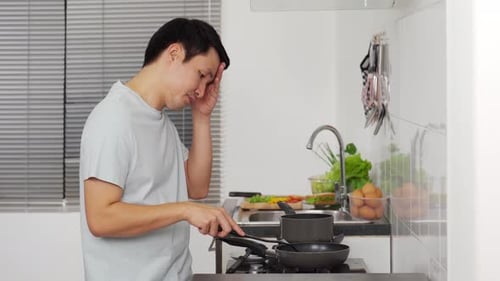 Man Cooking Food in Kitchen with Little Enthusiasm