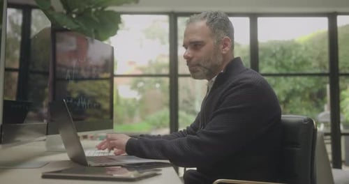 Successful Male Stockbroker Trading on Computer Terminal Sitting at Desk at Home