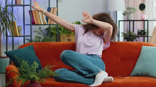 Femme tendance et joyeuse qui danse et bouge au rythme, faisant le geste de la gagnante de la danse dub, célébrez à la maison