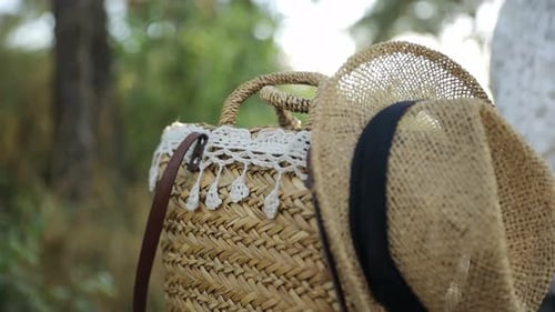 Una bolsa de paja y un sombrero cuelgan de un árbol