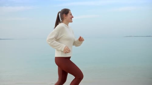 Young woman running on the sandy sea beach