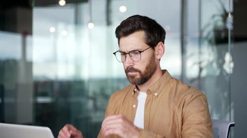 Man with Headache in Office Working on Laptop