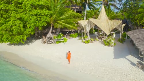 Beautiful Sexy Girl in a Red Dress Walking Down the White Sand Beach on a Paradise Tropical Island