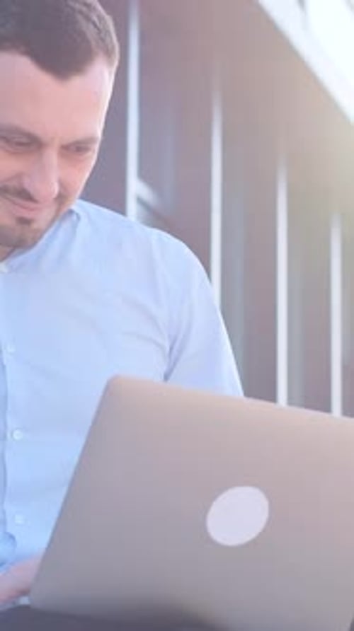 A Young Business Freelancer Works with a Laptop on the Street Near an Office Center Vertical Video