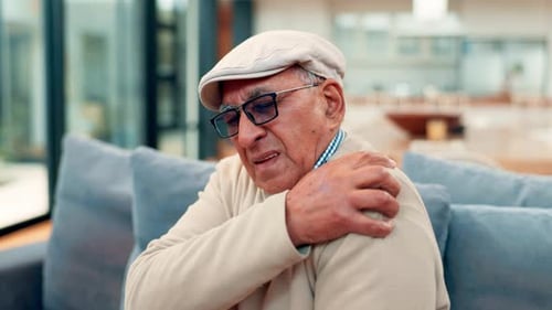 Senior Man Massaging His Aching Shoulder at Home