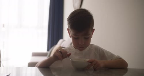 Boy Eating Cereal at Table Indoors