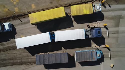 Cargo trucks lined up at a loading dock, sunny day, aerial view
