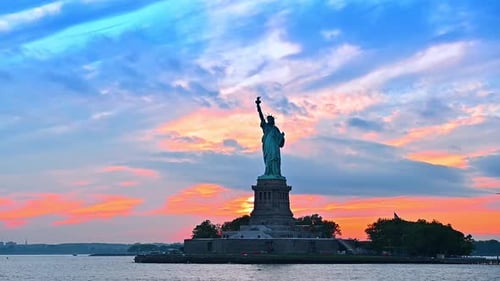 Blue and orange cloudy sky at sunset. Low angle view at the Statue of Liberty in New York, USA.