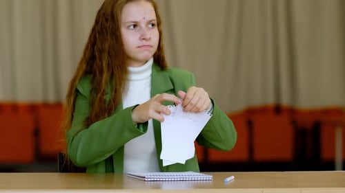 Angry Teenage Girl in Green Blazer Reads Something in Her Notebook and Then Tears the Sheet in Half