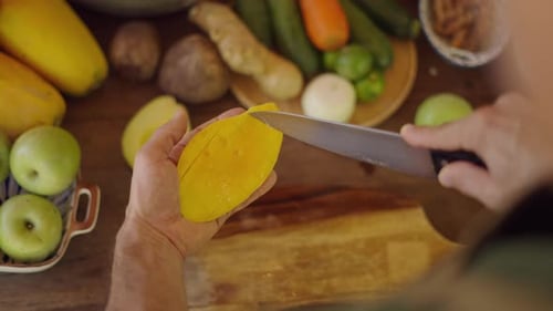 Hands of Person Cutting Mango Open