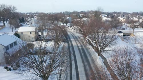 Snowstorm in USA. American homes in residential development. Aerial in winter snow. Snowflakes fall