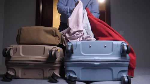 Man Packing Suitcase with Clothes Indoors for Travel