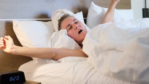 Fair Haired Woman Waking Up in Bed and Stretching