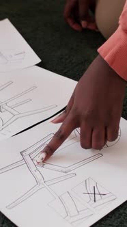 Mains d'un couple pointant du doigt des papiers avec instructions d'assemblage de la chaise