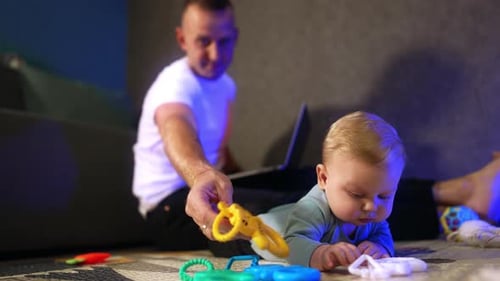 Baby Playing with Toys While Father Works