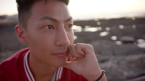Happy asian man looking away at beach, slow motion