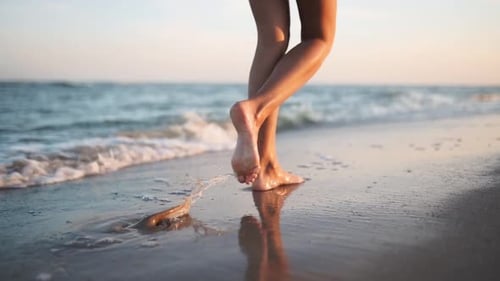 Slim Female Legs and Feet Walking Along Sea Water Waves on Sandy Beach Pretty Woman Walks at Seaside