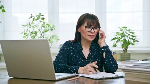 Businesswoman Discussing Plans on Phone in Office