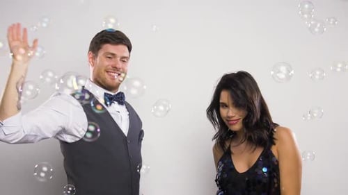 Cheerful Couple Dancing with Bubbles in Studio Setting