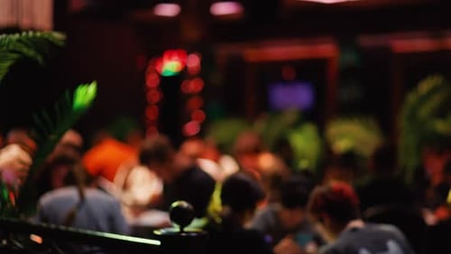 The Blurry Background Shows a Vibrant Restaurant Atmosphere with Lush Plants and Diverse People