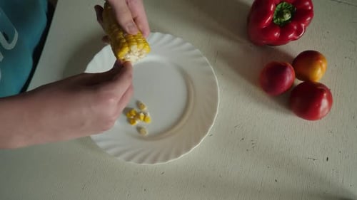 Hands Removing Corn Kernels on Plate at Table