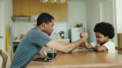 Father and Child Arm Wrestling at Kitchen Table