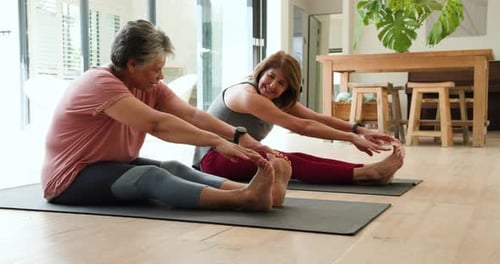 Senior women stretching on yoga mats at home, enjoying exercise together