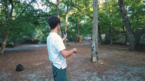young teenage man throwing axe into tree trunk in forest in fontainebleau sport
