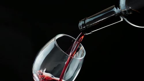 Pouring Red Wine into Glass on Black Background