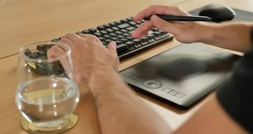Creative Professional Using Keyboard and Graphic Tablet at Desk