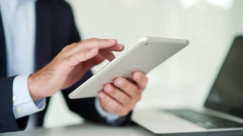 Close up of male hands holding and typing on digital tablet. Businessman in formal suit is using